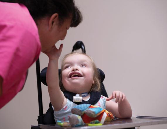 A child at Cedarcrest Center for Children with Disabilities enjoys time with a nurse assistant during a telemedicine session. Photo by Mark Washburn