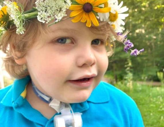 Isaac, a little boy, wears a crown of flowers.