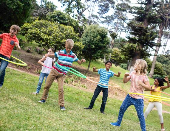 Six children, in two rows of three, hula-hoop outside.