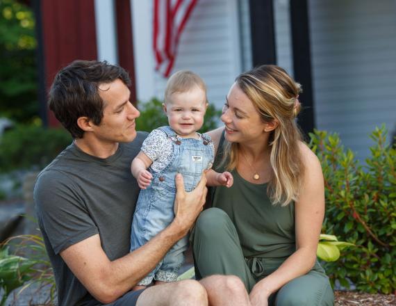 Parents sit together and hold their smiling baby.