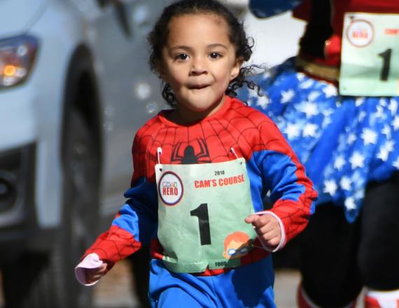 A young girl dressed in a Spider-Man costume runs in the CHaD Hero.