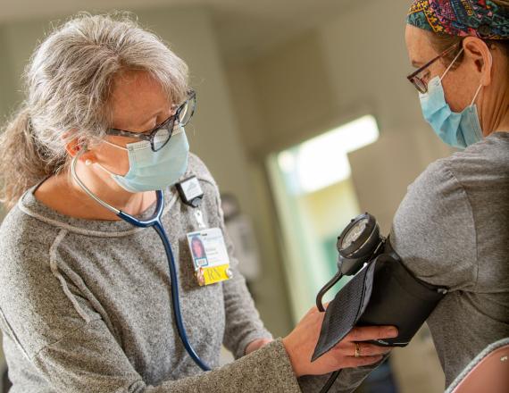 A nurse takes a patient's blood pressure.