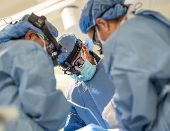 Three surgeons perform surgery.