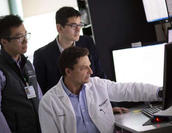 Three researchers at a computer screen