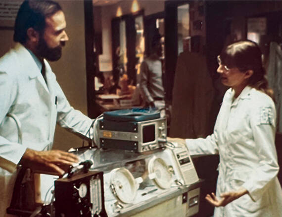 Intensive Care Nursery founder and medical director George Little, MD, and head nurse Linda Brown, RN, work with the original transport isolette in the early days of the Intensive Care Nursery.