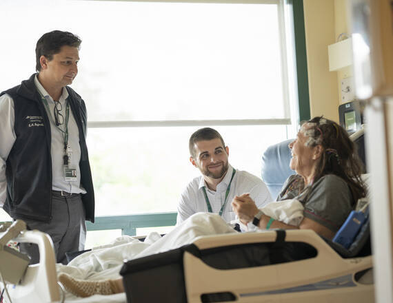 Two caregivers visiting a patient at the bedside