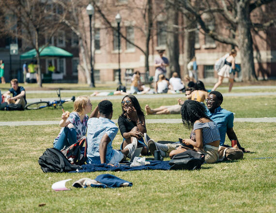 Dartmouth undergraduate students sitting on the Dartmouth Green on a warm spring day.